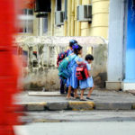 一辆红色的公共汽车经过穿着制服的孩子们。交通和与城市的融合是为所有人提供可达性的关键。Greg Younger拍摄。